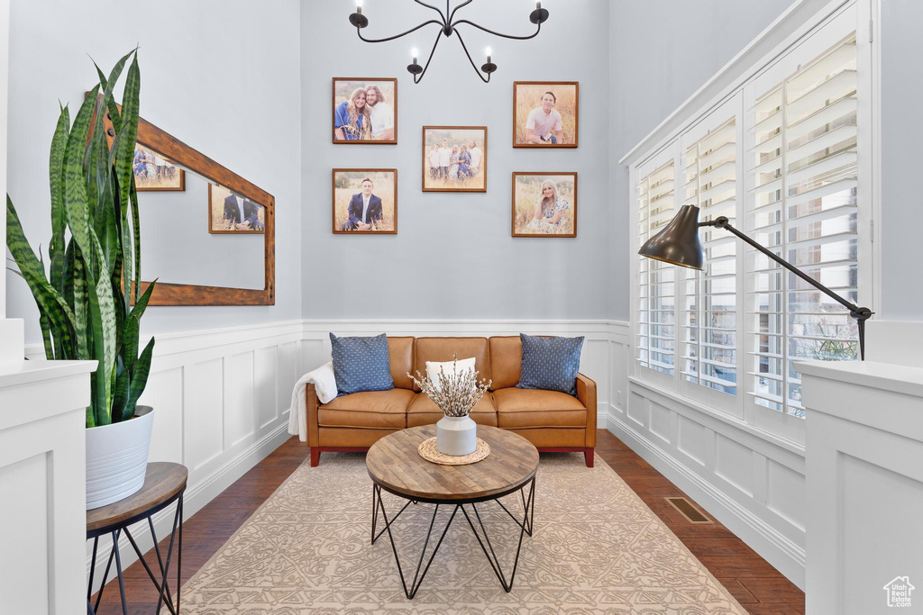 Sitting room featuring wood finished floors, a decorative wall, wainscoting, and a chandelier