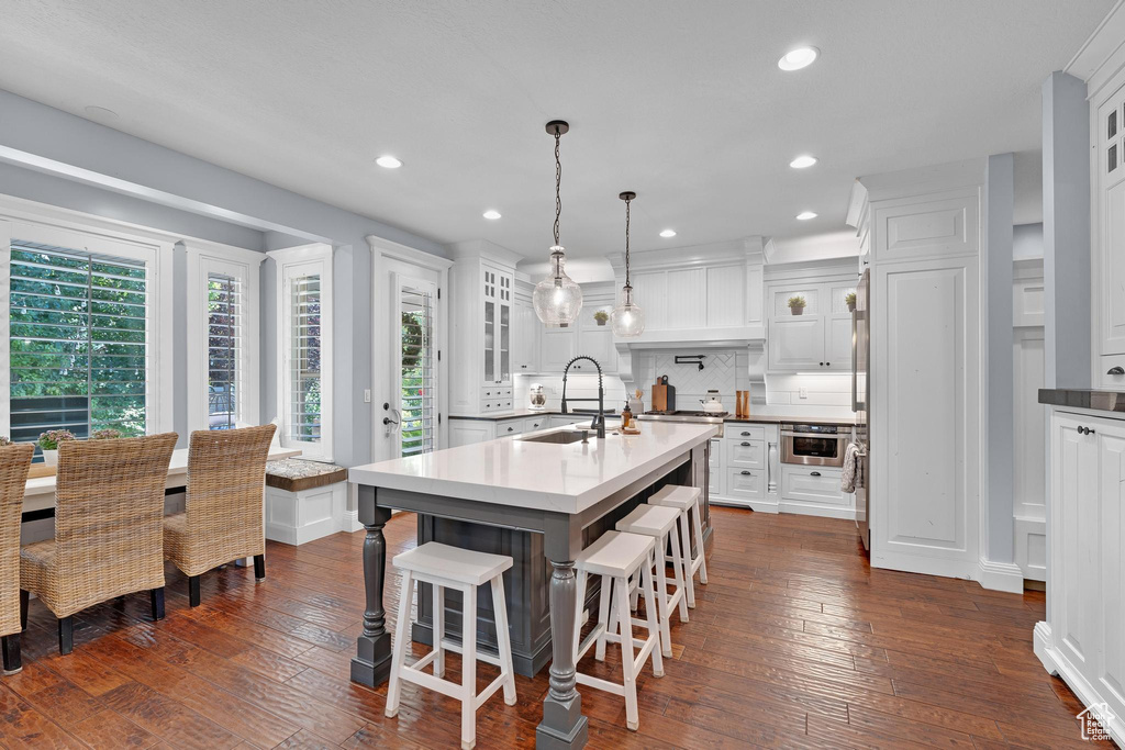 Kitchen featuring a sink, decorative backsplash, dark wood-style flooring, white cabinets, and recessed lighting