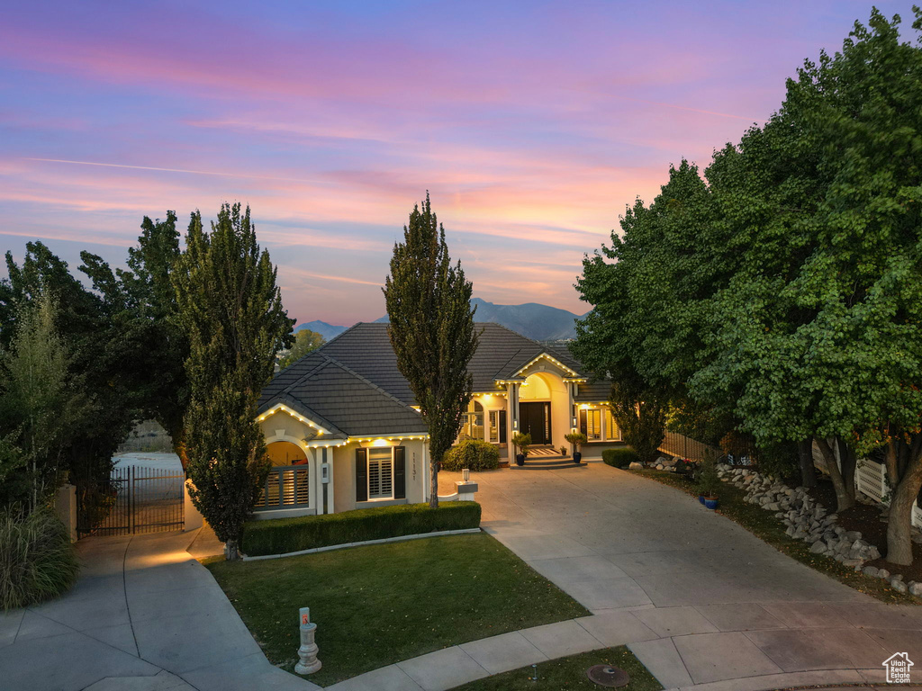 View of front of house featuring driveway, a gate, stucco siding, and a tiled roof