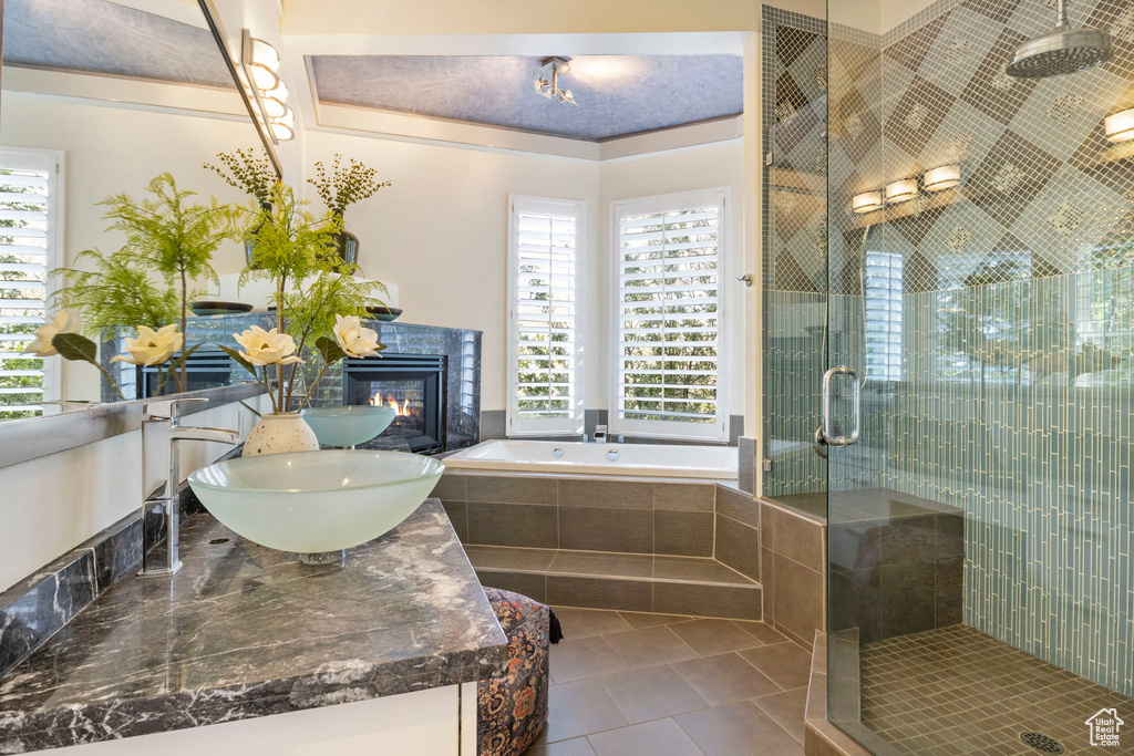 Bathroom with a stall shower, tile patterned flooring, a bath, a tiled fireplace, and vanity