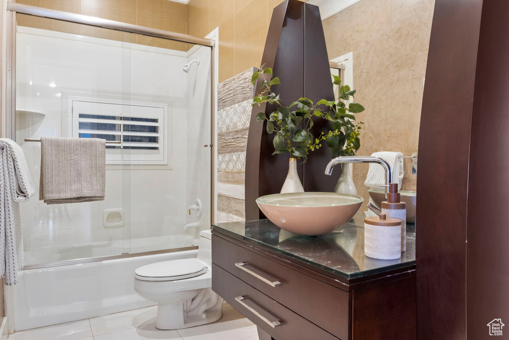 Full bath featuring tile patterned flooring, combined bath / shower with glass door, vanity, and toilet