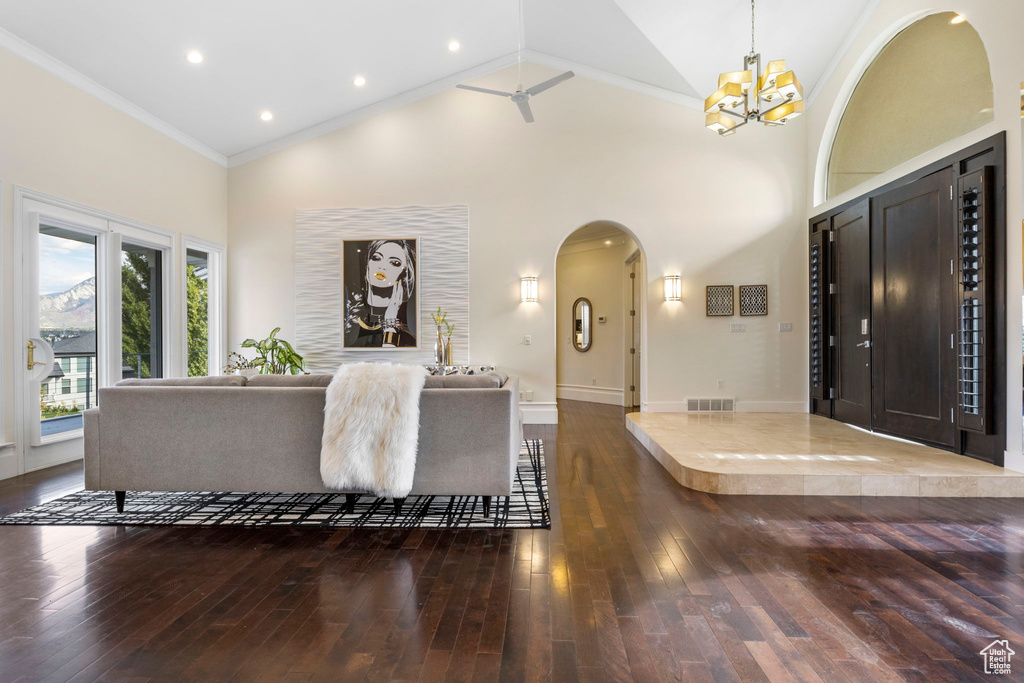 Entrance foyer with arched walkways, wood-type flooring, high vaulted ceiling, a chandelier, and baseboards