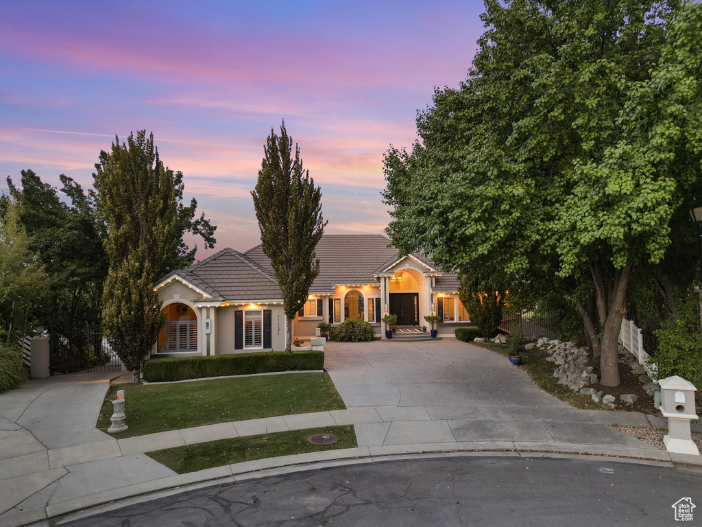 View of front of property with concrete driveway, a front lawn, a tiled roof, and stucco siding