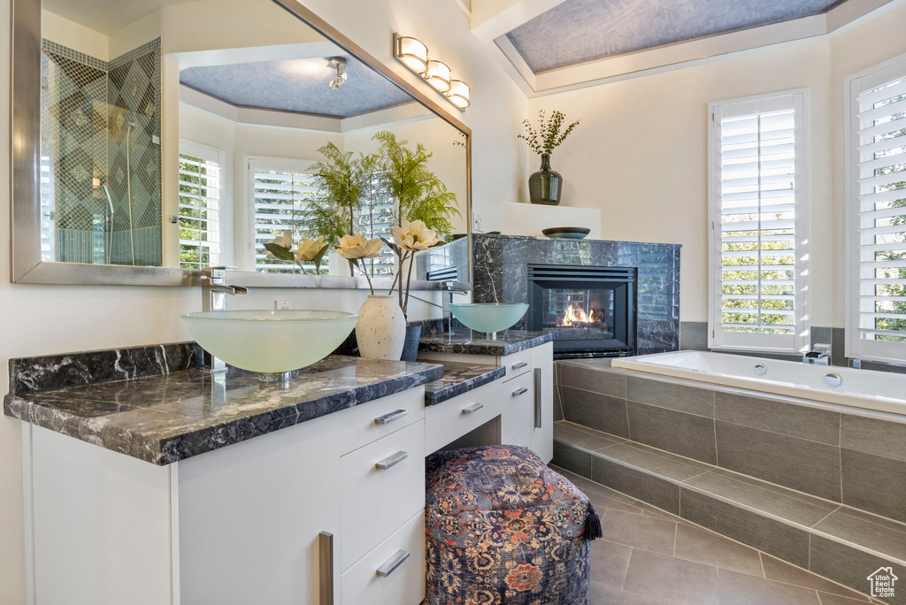 Full bathroom featuring a tile fireplace, tile patterned flooring, a garden tub, and double vanity