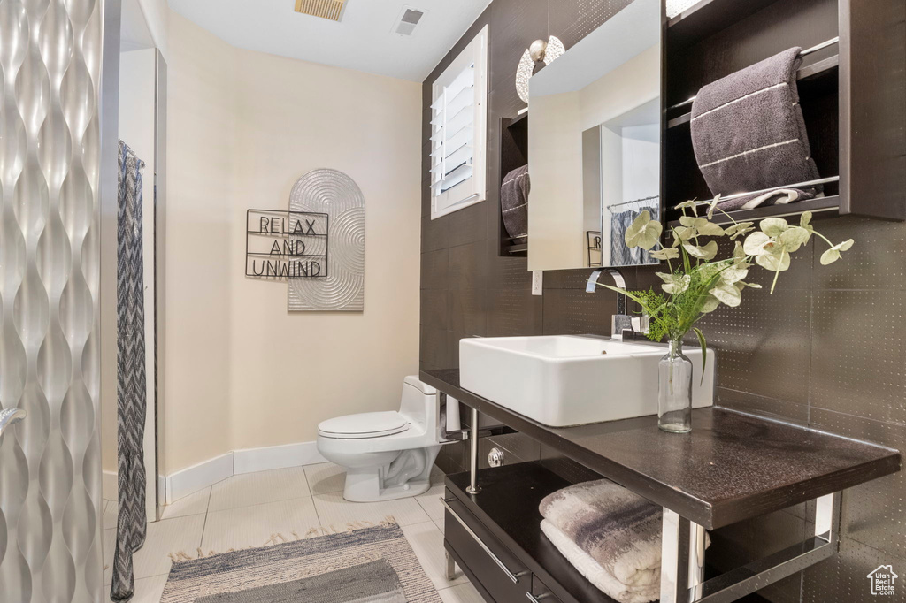 Bathroom featuring toilet, tile patterned floors, baseboards, and vanity