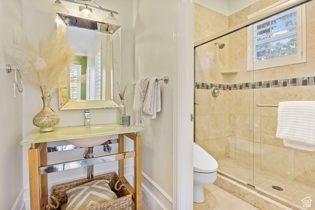 Bathroom with toilet, a shower stall, a sink, and baseboards