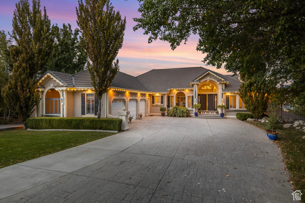 View of front of house with a garage, a yard, a tiled roof, and driveway