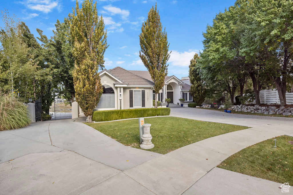 View of front of property featuring a gate, concrete driveway, and stucco siding