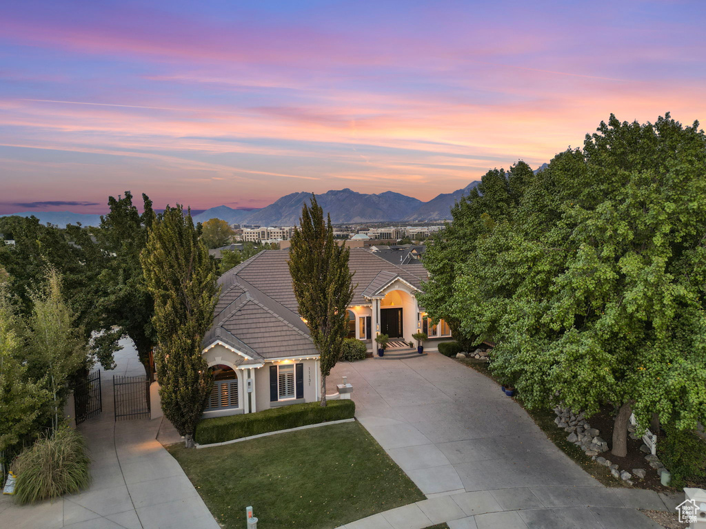 View of front facade featuring driveway, a tiled roof, a gate, stucco siding, and a mountain view