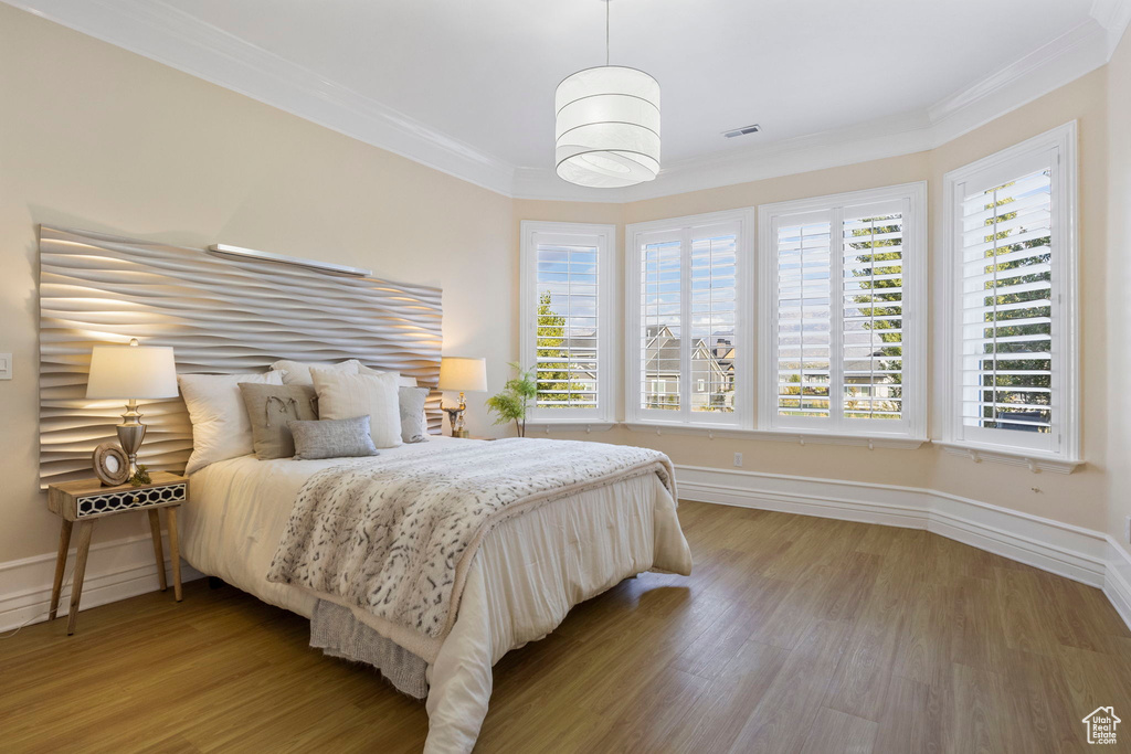 Bedroom with crown molding, multiple windows, light wood-style floors, and baseboards