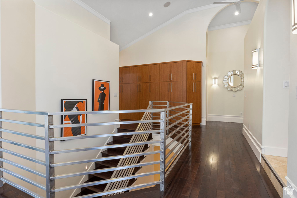 Stairs featuring high vaulted ceiling, hardwood / wood-style flooring, crown molding, and baseboards