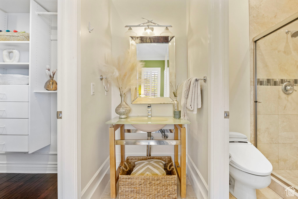 Full bath with a shower stall, toilet, and wood finished floors