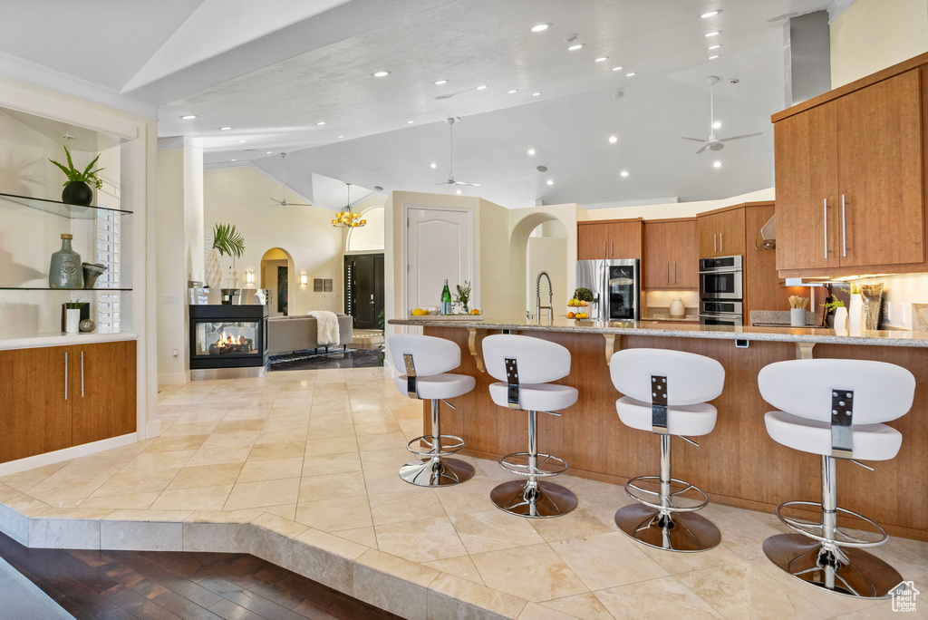 Kitchen featuring appliances with stainless steel finishes, brown cabinetry, arched walkways, recessed lighting, and a peninsula