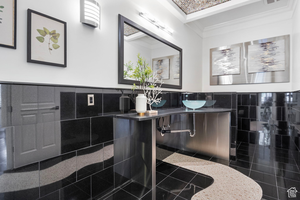 Bathroom with tile walls, granite tiled floors, wainscoting, crown molding, and vanity