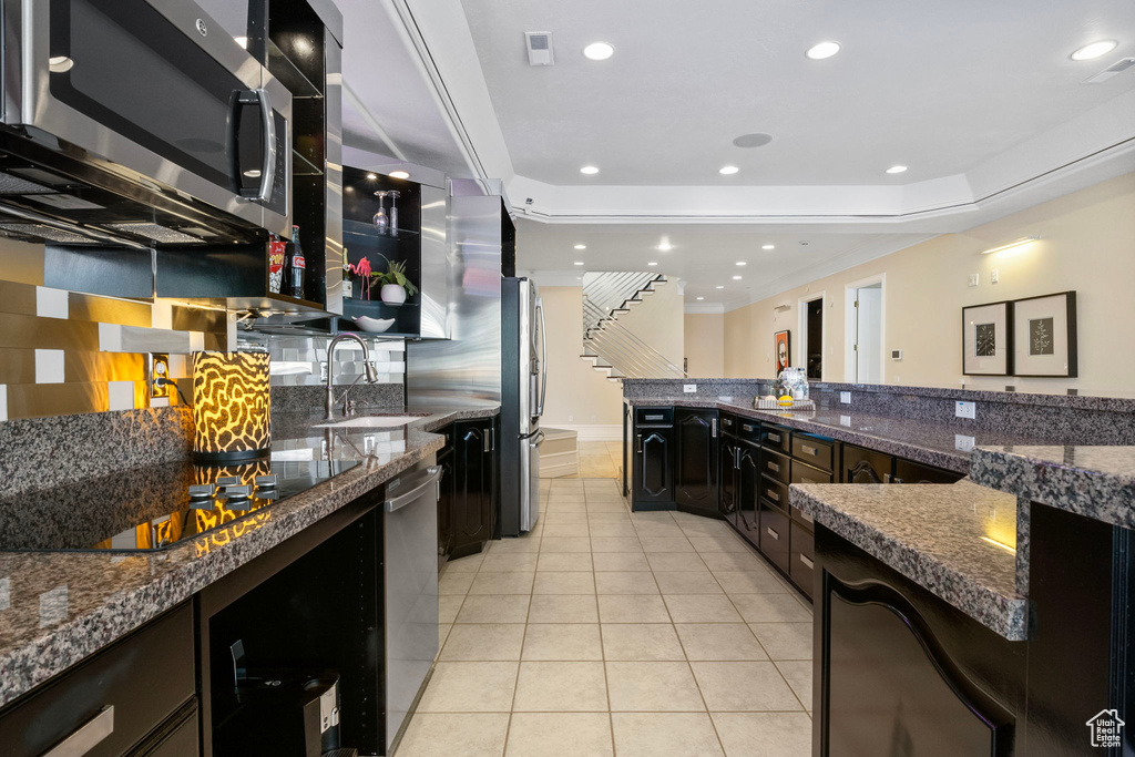 Kitchen with appliances with stainless steel finishes, a sink, decorative backsplash, light tile patterned floors, and recessed lighting