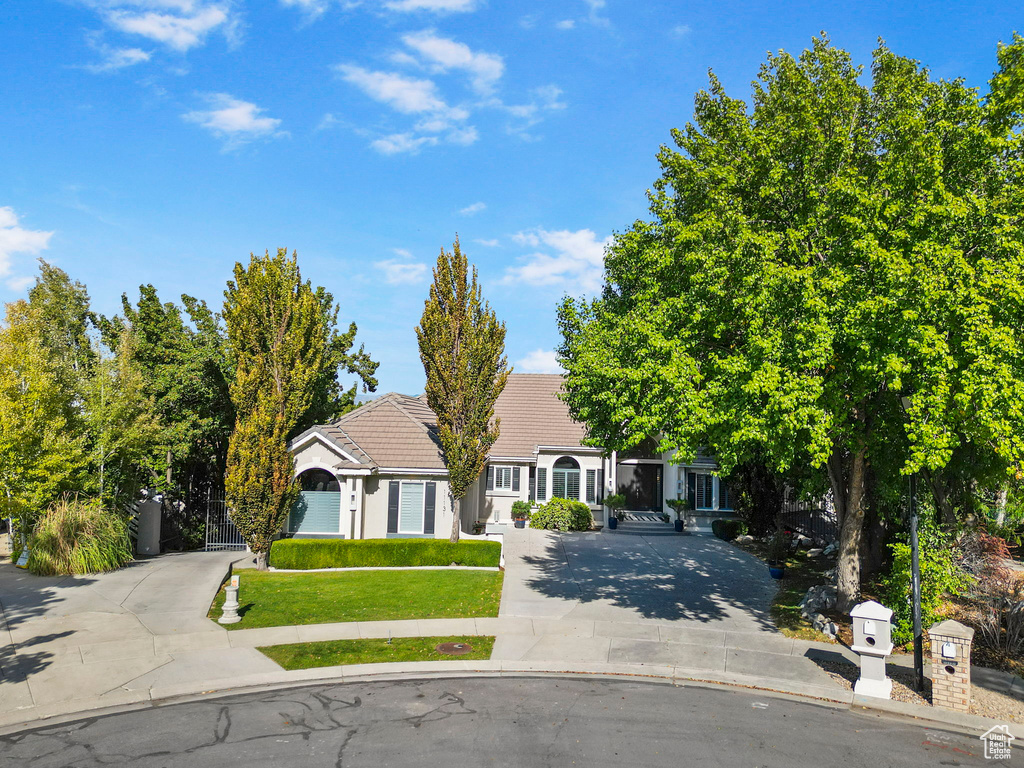 View of front of house with driveway, a tiled roof, and a gate