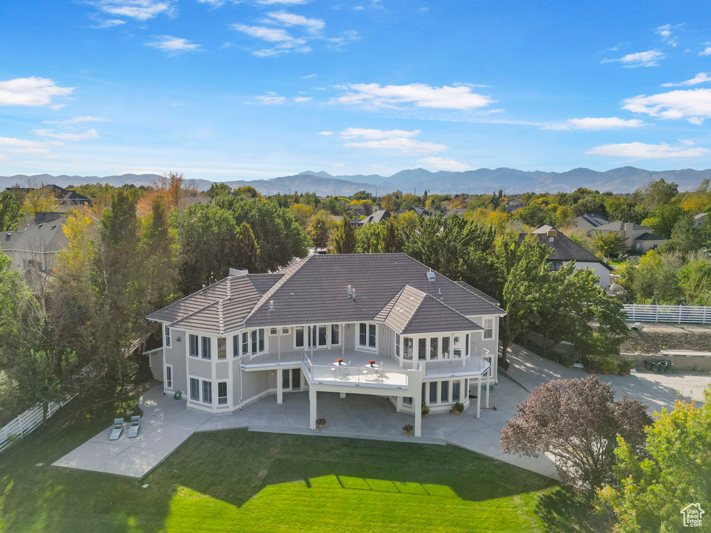 Rear view of property featuring a patio area, a lawn, and a mountain view