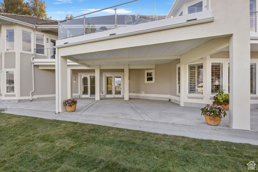 Rear view of property featuring stucco siding, a patio area, and a yard