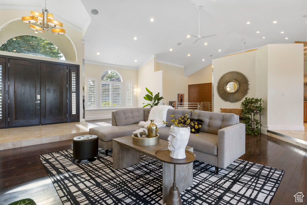 Living room featuring crown molding, hardwood / wood-style floors, high vaulted ceiling, baseboards, and a chandelier