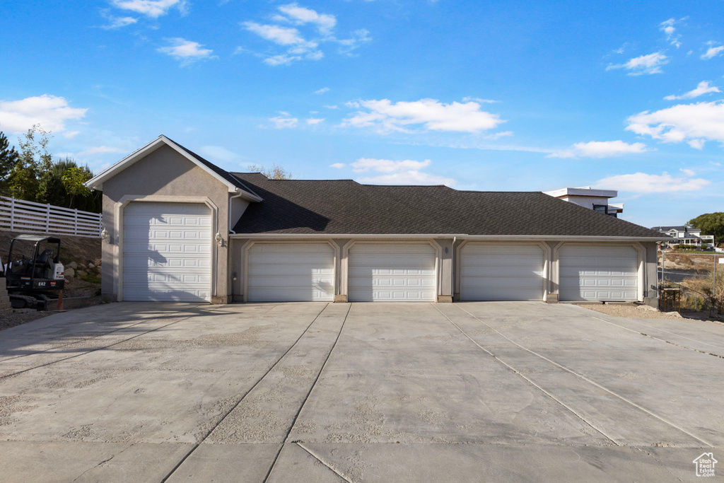 Ranch-style house featuring concrete driveway, a garage, a shingled roof, and fence