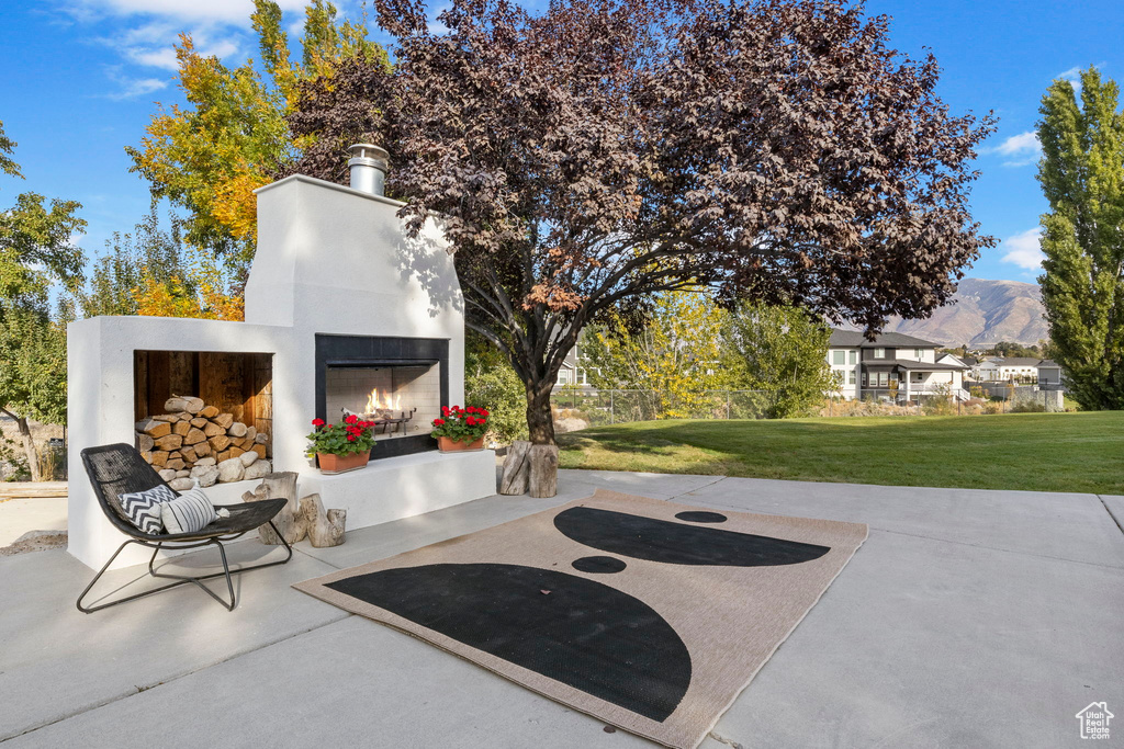View of patio / terrace featuring a warm lit fireplace and a mountain view