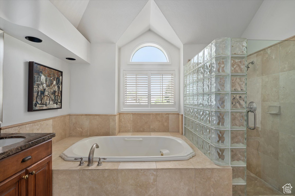 Bathroom with tiled shower, lofted ceiling, a garden tub, and vanity