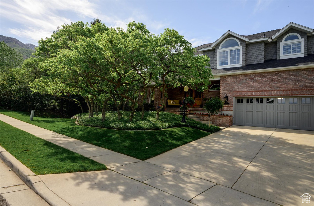 View of front of house with concrete driveway, a front lawn, brick siding, and a garage