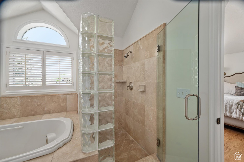Ensuite bathroom with vaulted ceiling, a stall shower, healthy amount of natural light, and a garden tub