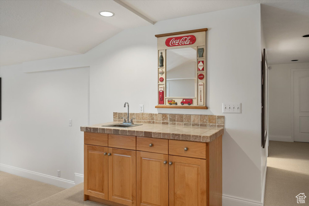 Indoor wet bar featuring light colored carpet, baseboards, lofted ceiling, and recessed lighting