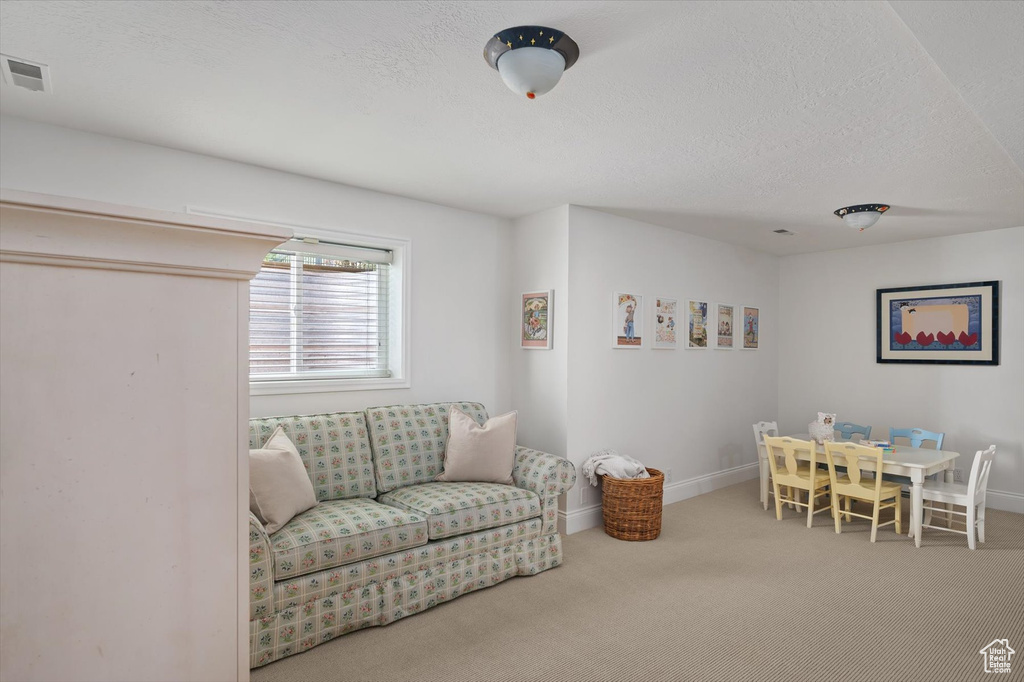 Living area with carpet flooring, a textured ceiling, and baseboards