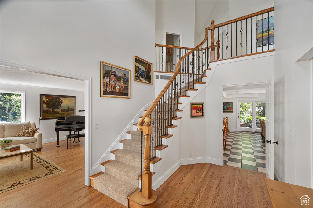 Stairway with wood finished floors, a towering ceiling, and baseboards