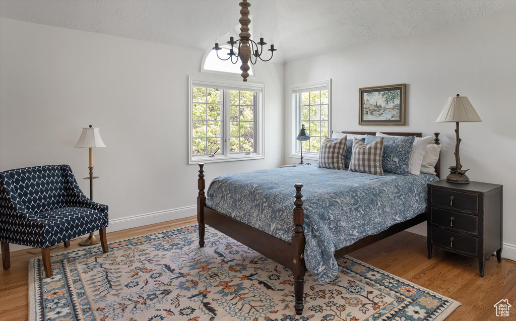 Bedroom with wood finished floors, baseboards, and a textured ceiling