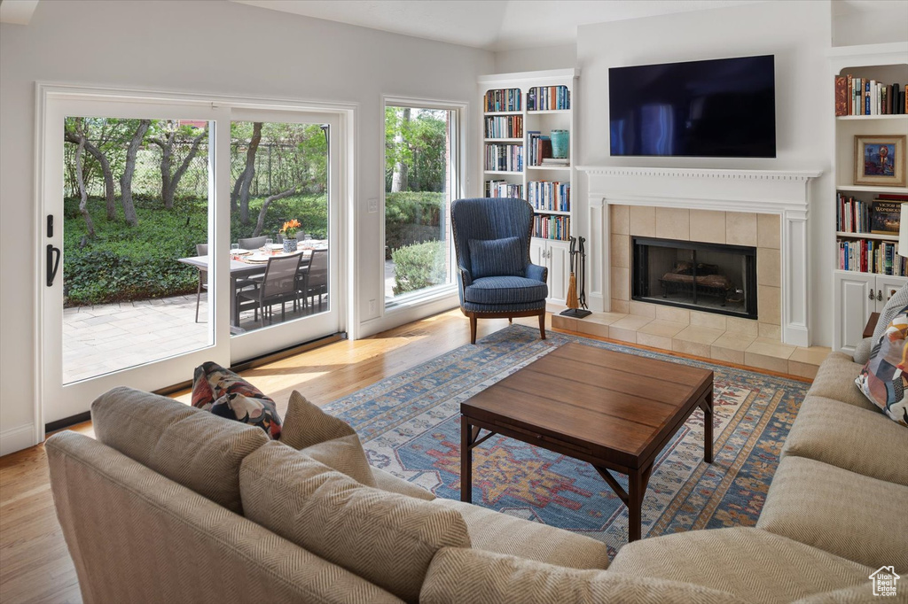 Living area with wood finished floors, a fireplace, and built in shelves