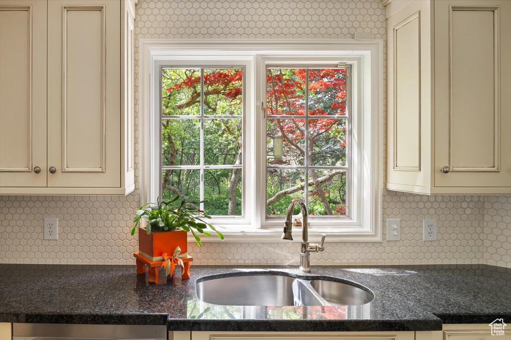 Kitchen featuring a sink, cream cabinetry, dishwasher, and tasteful backsplash