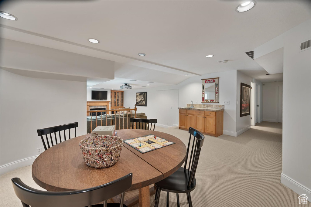 Dining room with baseboards, wet bar, light colored carpet, recessed lighting, and a fireplace