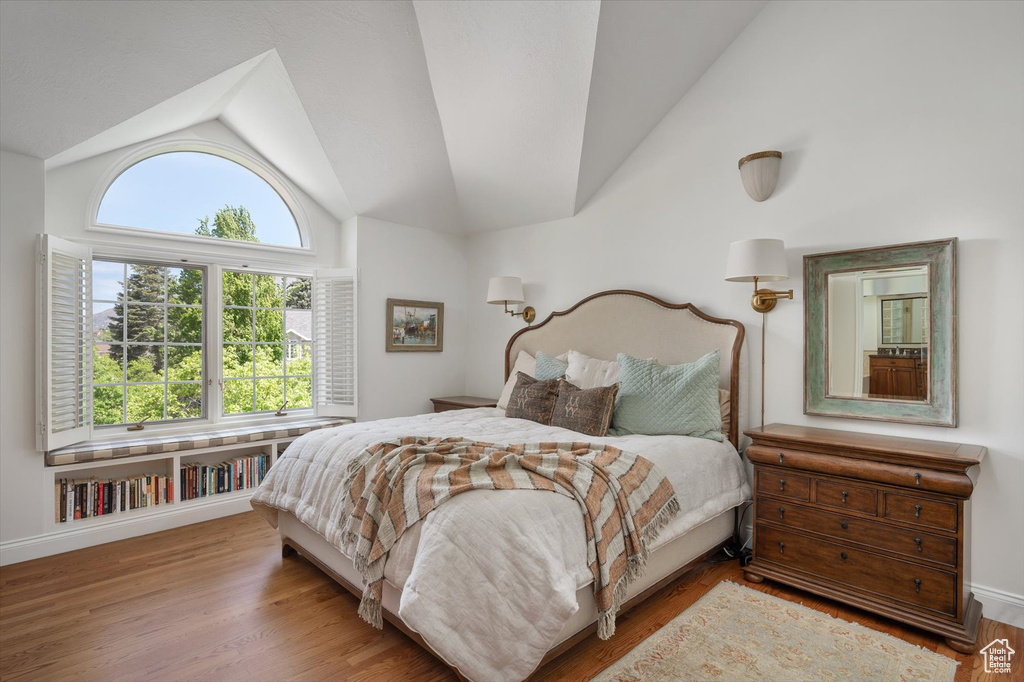 Bedroom featuring lofted ceiling, multiple windows, wood finished floors, and baseboards