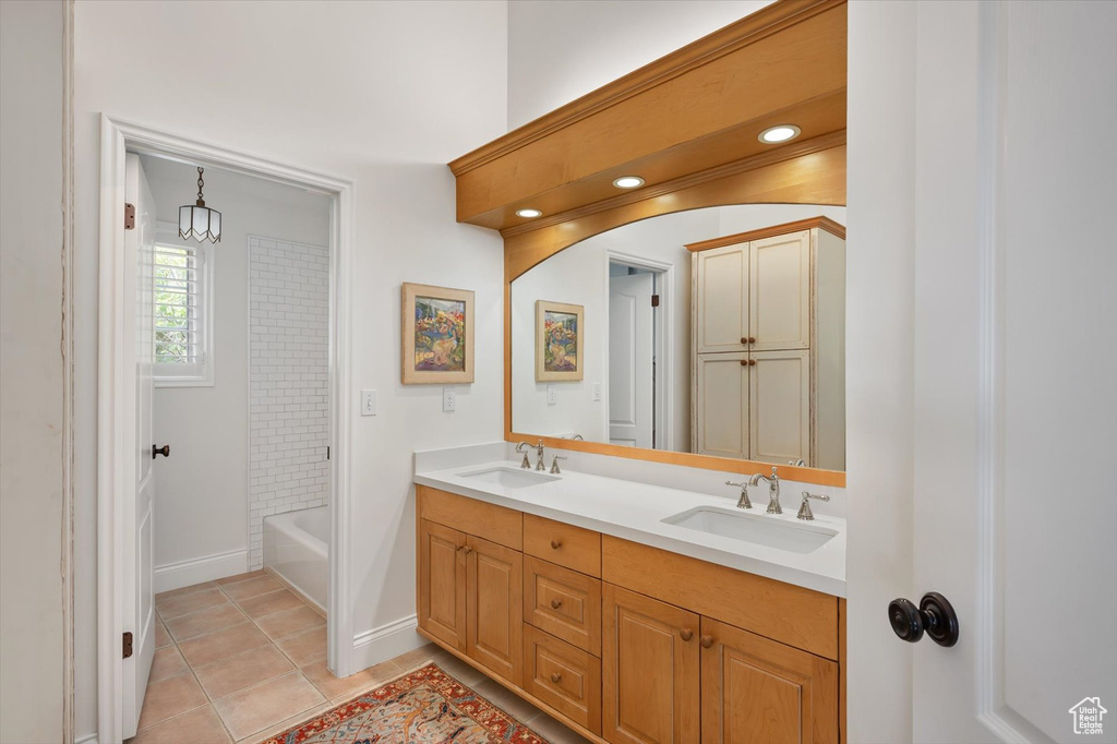 Bathroom featuring double vanity, tile patterned flooring, and baseboards