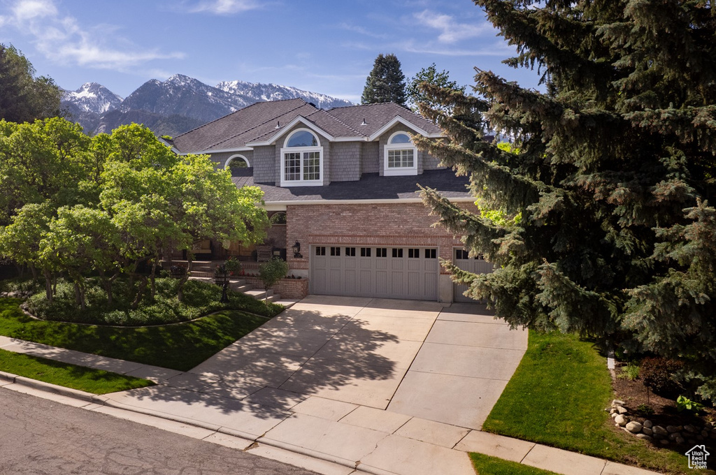 View of front facade featuring driveway, brick siding, an attached garage, and a mountain view