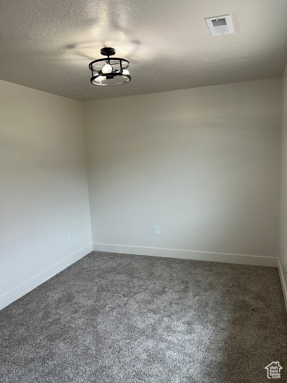 Carpeted empty room featuring baseboards and a textured ceiling