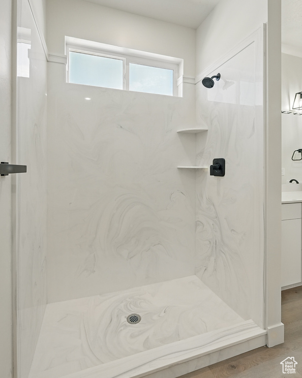 Bathroom featuring a marble finish shower, vanity, and wood finished floors
