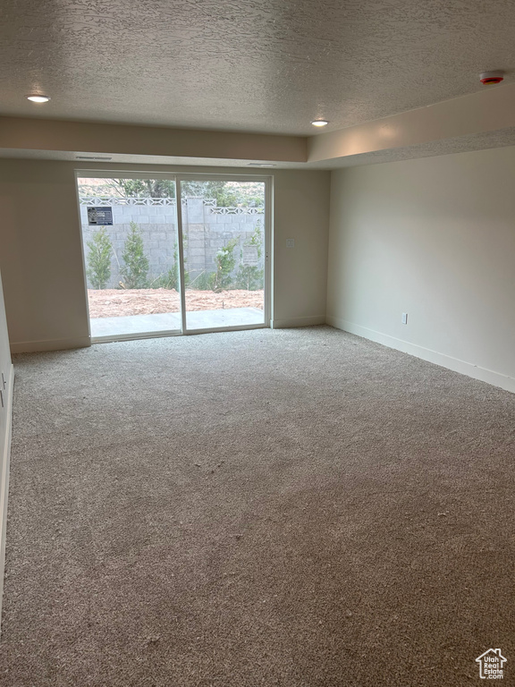 Spare room with a textured ceiling, carpet floors, baseboards, and a smoke detector