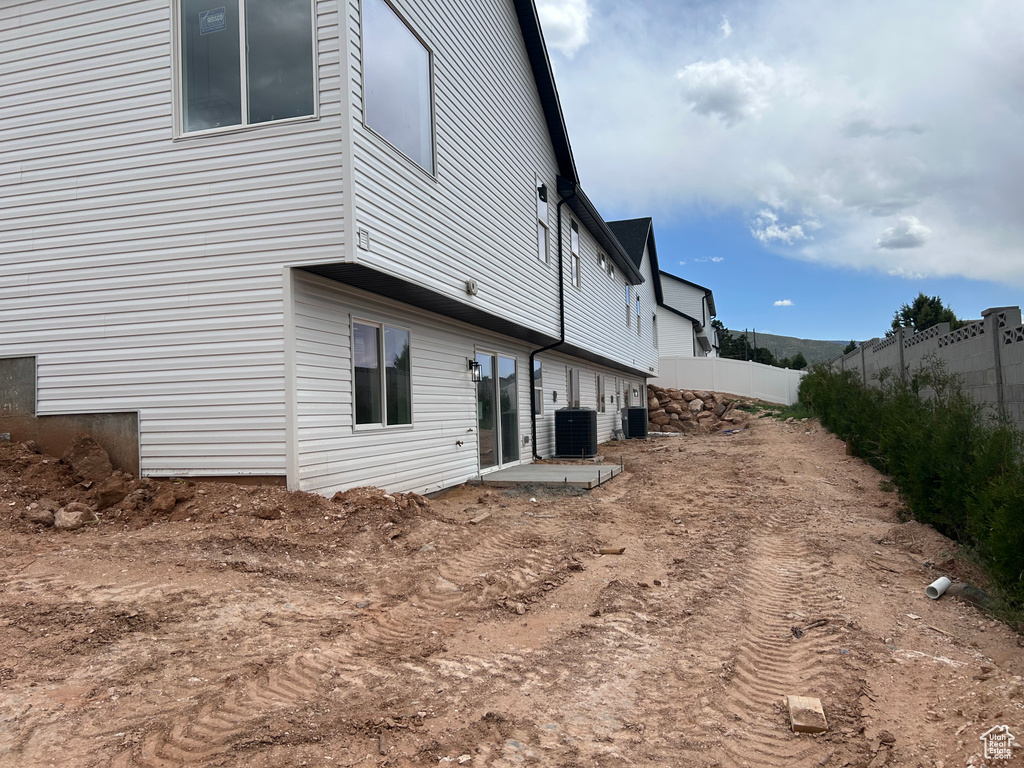 Back of property featuring central AC unit and fence