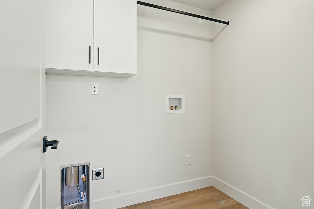 Laundry area with cabinet space, hookup for an electric dryer, hookup for a washing machine, light wood-type flooring, and baseboards