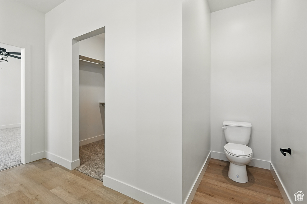 Bathroom featuring wood finished floors, toilet, and baseboards