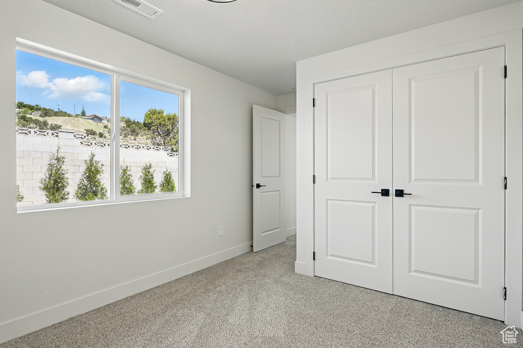 Unfurnished bedroom featuring baseboards, light colored carpet, and a closet