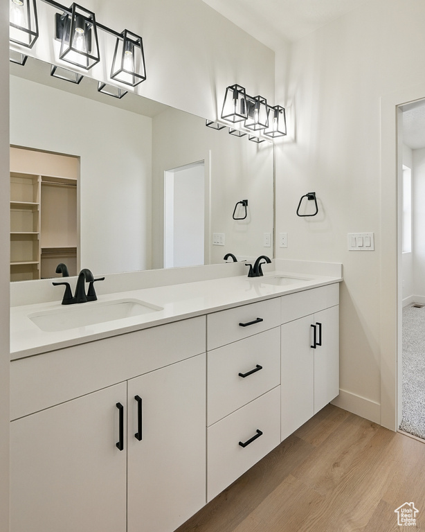 Bathroom featuring wood finished floors, double vanity, and baseboards