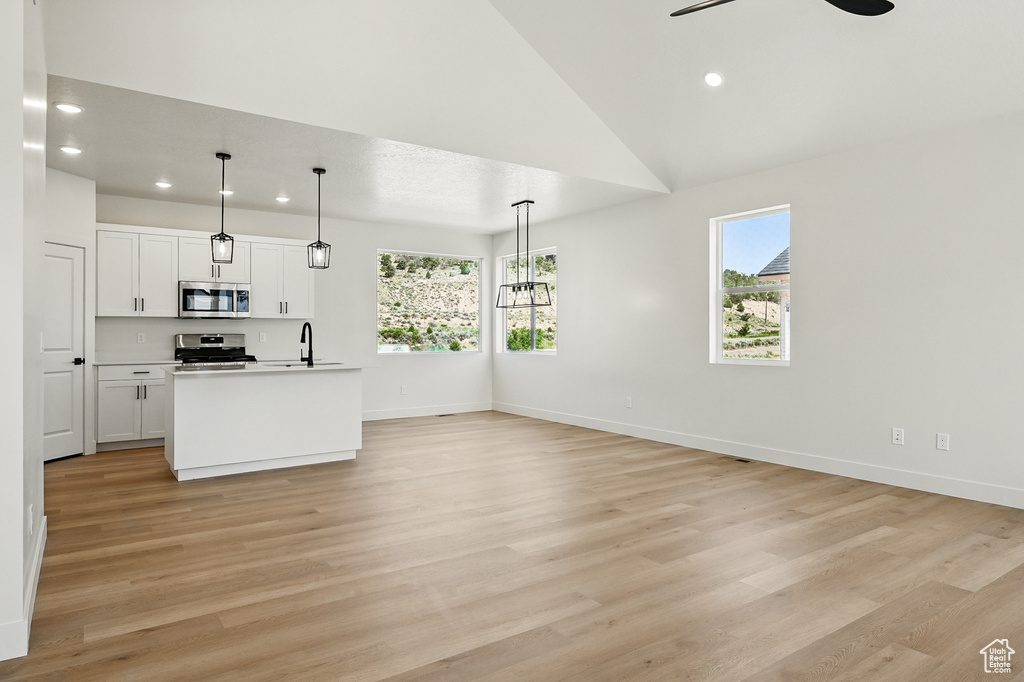 Kitchen with stainless steel appliances, plenty of natural light, recessed lighting, light wood-type flooring, and vaulted ceiling