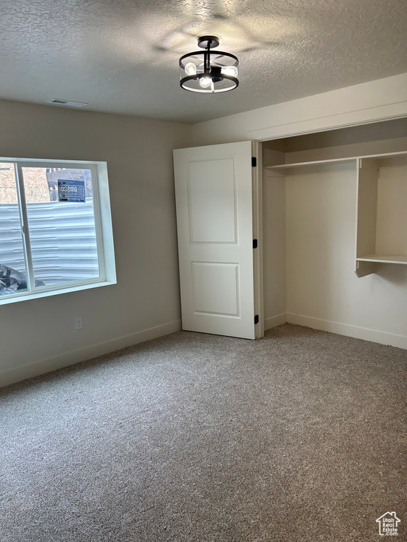 Unfurnished bedroom with a textured ceiling, carpet flooring, baseboards, and a closet