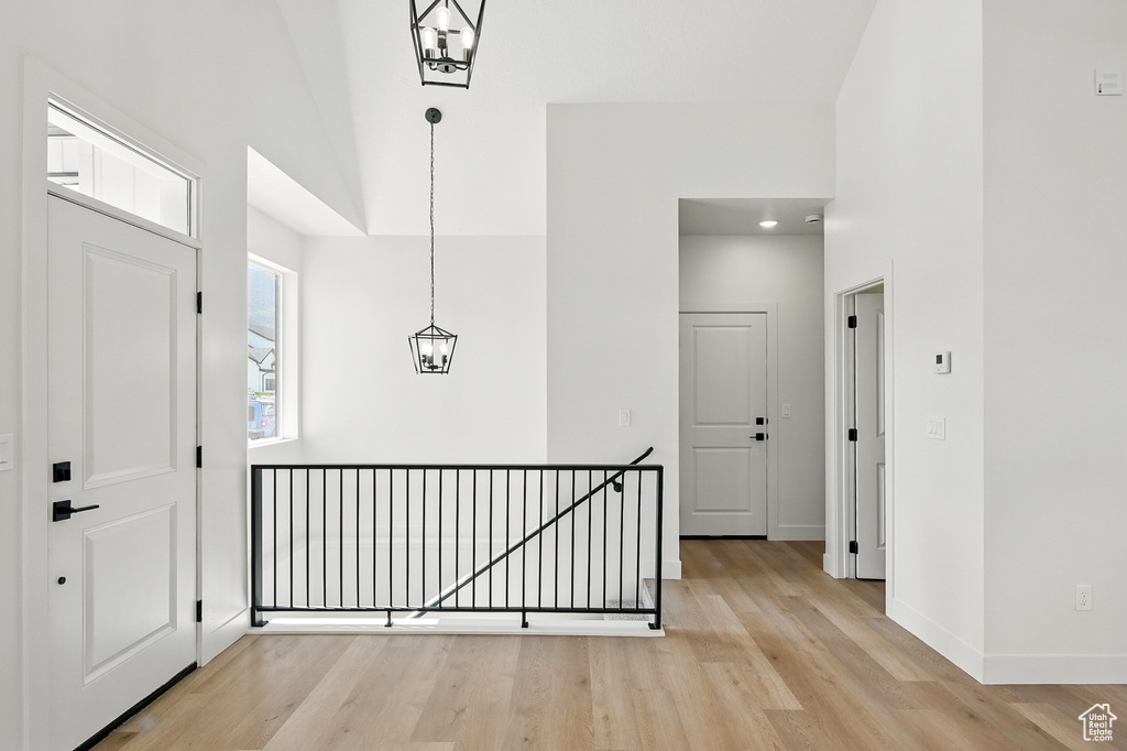 Foyer entrance featuring a towering ceiling, light wood-type flooring, baseboards, and a chandelier