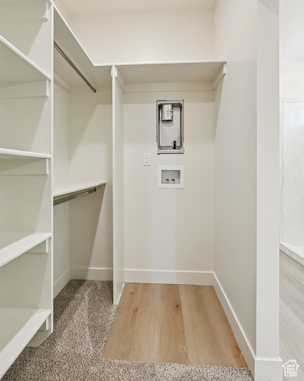 Laundry area with hookup for a washing machine, wood finished floors, and baseboards